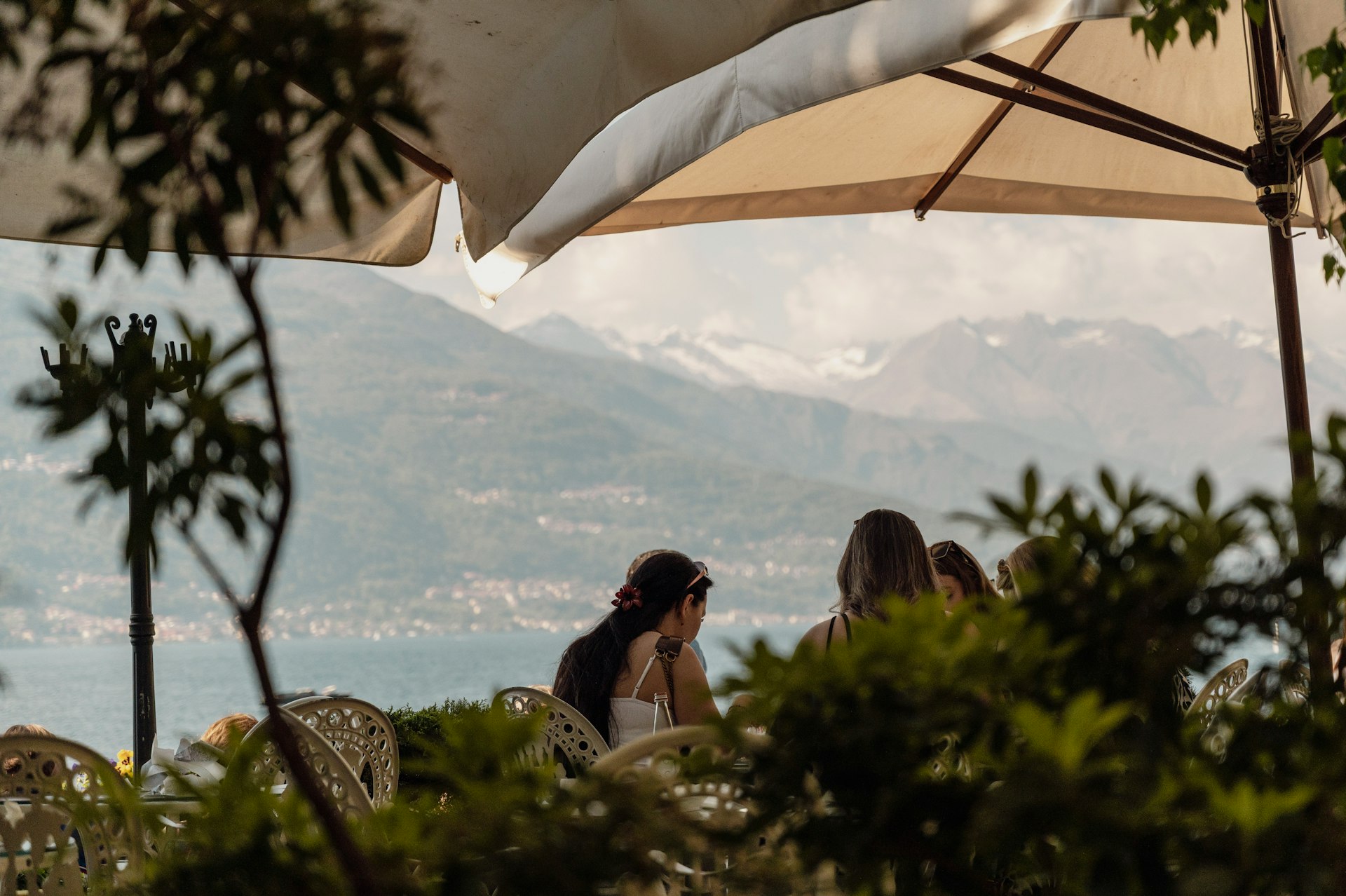 People under an umbrella with mountains and a lake.